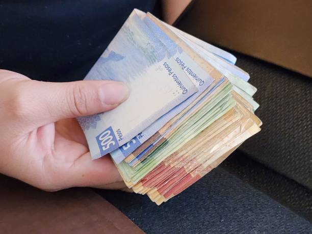 approach to hand of a woman holding mexican banknotes