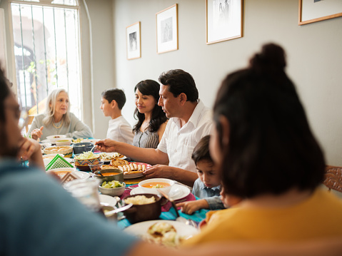 A mexican family talking and eating tasty mexican food during a meal.